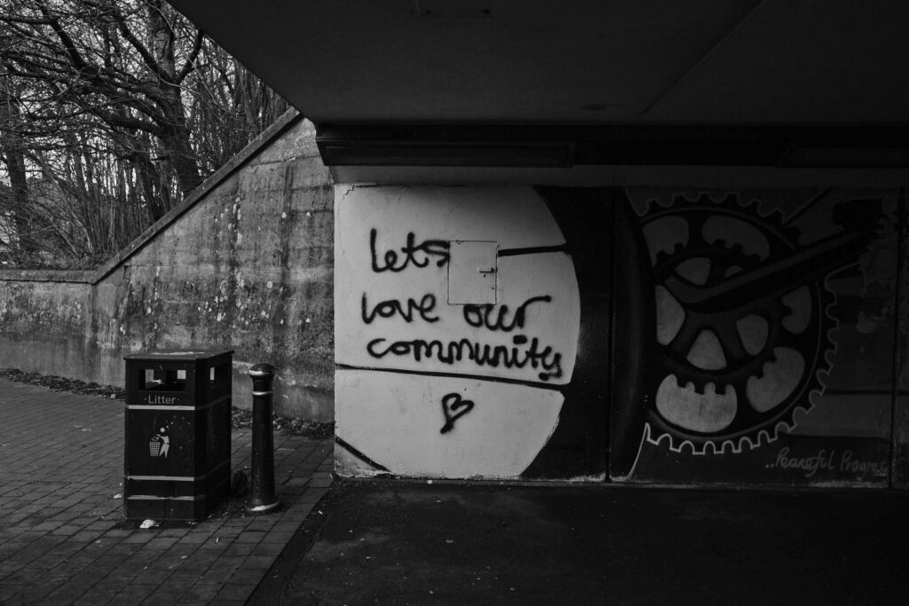 Black and white image of a wall with graffiti that reads "let's love our community"
